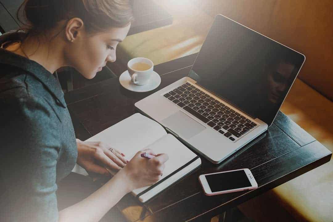 woman taking notes while writing her perfect resume