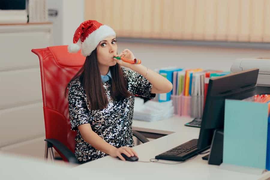 woman in santa hat working on linkedin profile and blowing party horn
